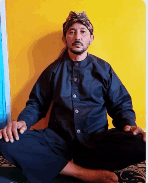 a man in a black shirt sits on the floor