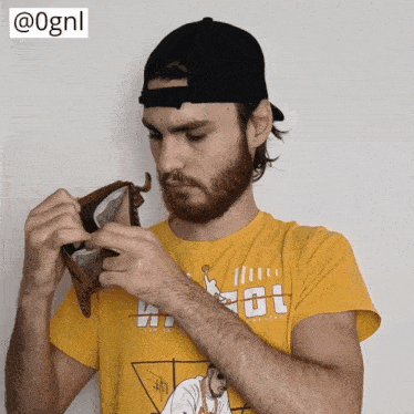 a man with a beard wearing a yellow t-shirt that says ' aot ' on it