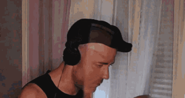 a man wearing headphones and a hat looks down at something