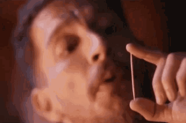 a man is holding a small object in his hand in front of his face .