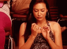 a woman in a leopard print dress is sitting in a chair holding her hands together .