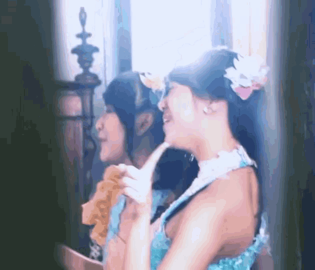 a woman in a blue dress is looking at her reflection in the mirror .