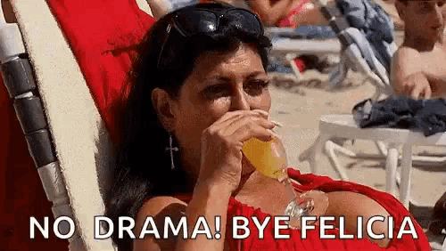 a woman is sitting in a chair on the beach drinking a glass of orange juice .