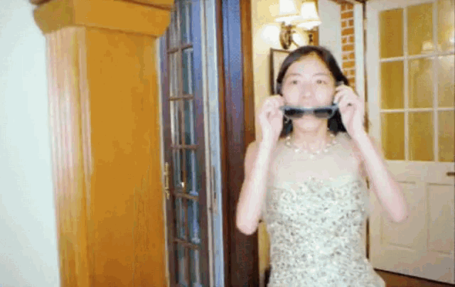 a woman in a dress is putting on sunglasses in a hallway