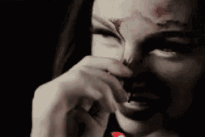 a woman with blood on her forehead is holding her hand to her face .
