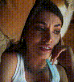 a woman in a white tank top is laying down and talking on a cell phone
