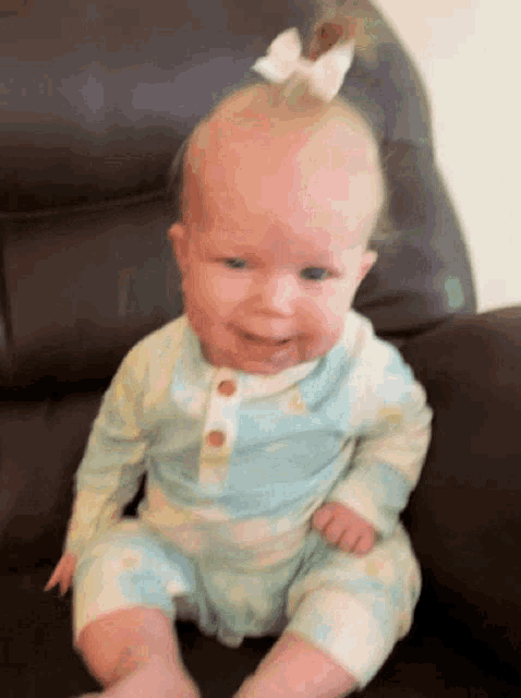 a baby with a bow on her head is smiling