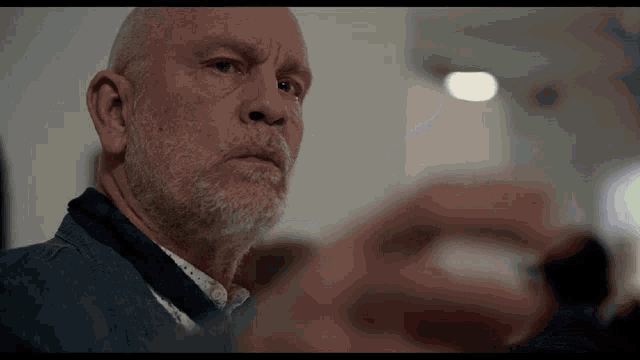 a bald man with a beard is looking at something