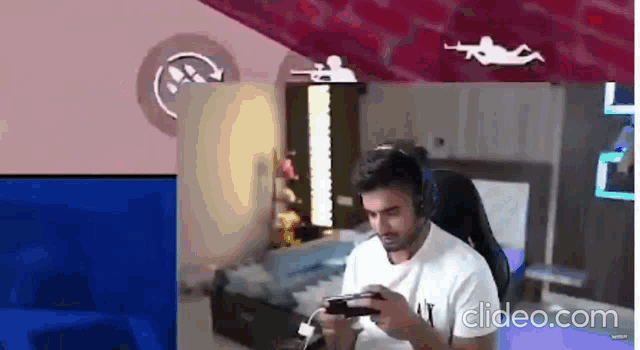 a man wearing headphones is playing a video game on a console .