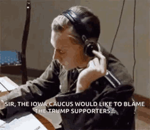 a man wearing headphones is talking on a microphone while sitting at a desk .