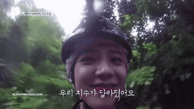 a woman is wearing a helmet and smiling while riding a bike in the woods .