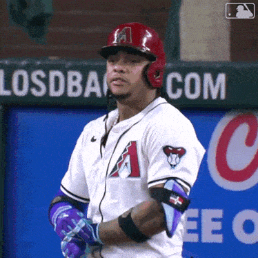 a baseball player stands in front of a sign that says losdback.com