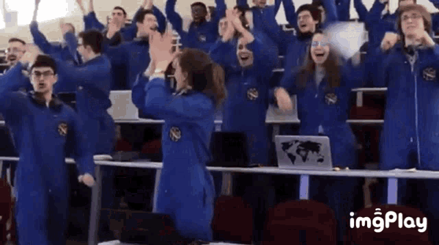 a group of people in blue jumpsuits are raising their hands in the air
