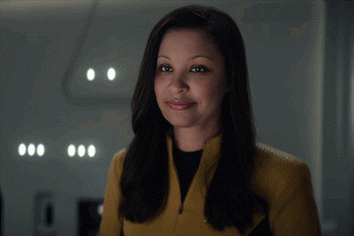 a woman wearing a yellow jacket and black shirt smiles at the camera