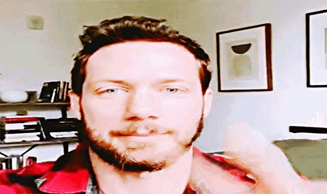 a man with a beard is wearing a red plaid shirt and giving a thumbs up