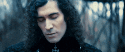 a man with long curly hair and a cross around his neck