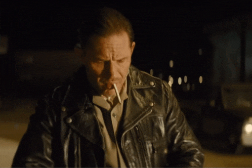 a man wearing a leather jacket smoking a cigarette