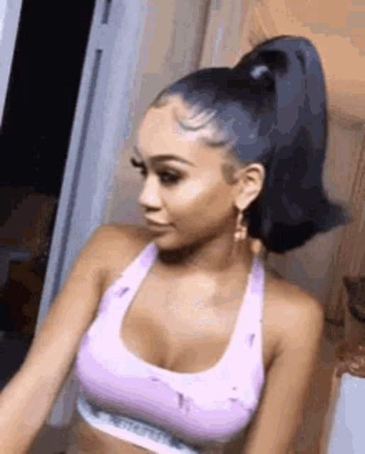 a woman with a ponytail is wearing a purple sports bra .