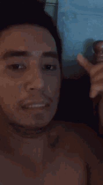 a man without a shirt is holding something in his hand and making a funny face