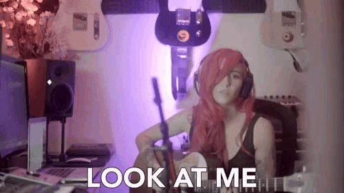 a woman with red hair is singing into a microphone with the words look at me below her
