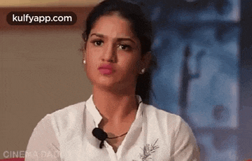 a woman wearing a white shirt and a microphone is making a face .