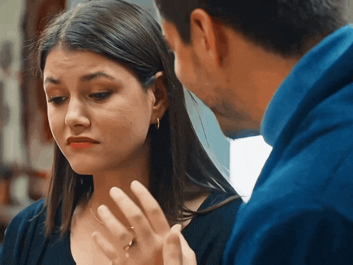 a man and a woman are looking at each other and the woman is wearing a ring on her finger
