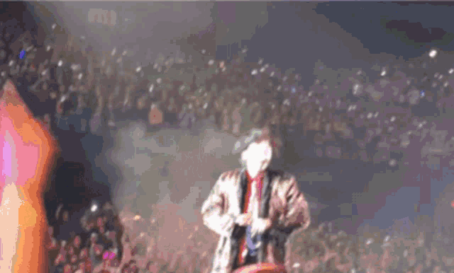 a man is singing into a microphone in front of a crowd .