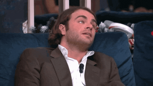a man in a suit sits on a blue couch