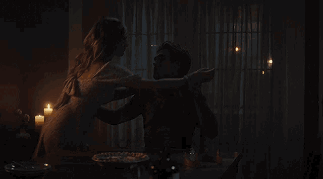 a man and woman are sitting at a table with candles on it