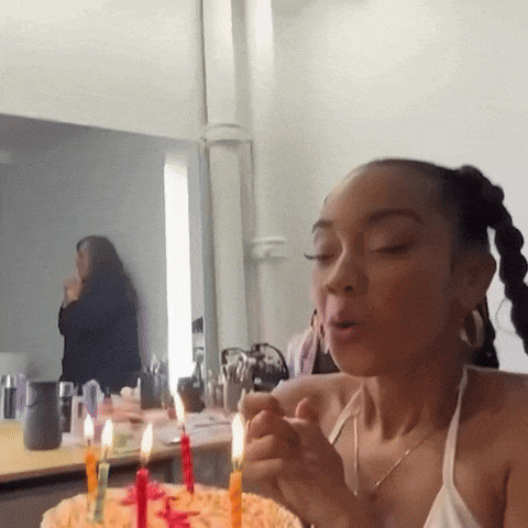 a woman is blowing out candles on a cake