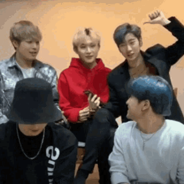 a group of young men are sitting next to each other and one of them is holding a cell phone .