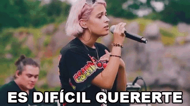 a woman is singing into a microphone with the words `` es dificil queerte '' written below her .