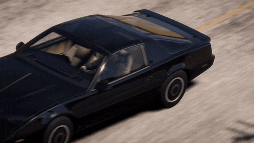 a black sports car with white tires is driving down a road