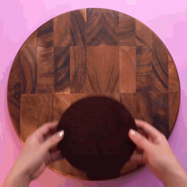 a person is holding a piece of cake on a wooden cutting board