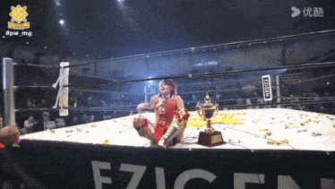 a woman in a wrestling ring with a trophy and a sign that says e7icn