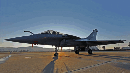 a fighter jet is parked on a runway with a shadow on the pavement