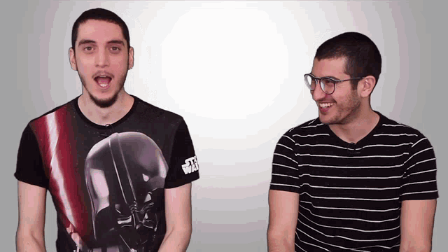 a man wearing a darth vader shirt is standing next to another man