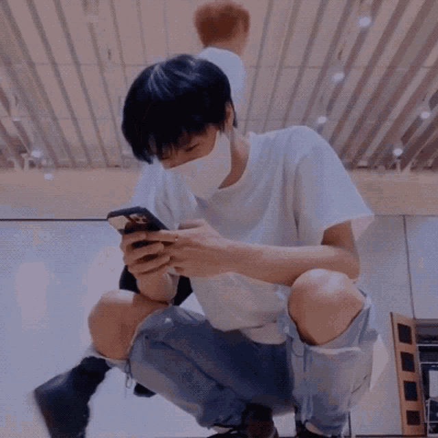 a man wearing a face mask looks at his phone