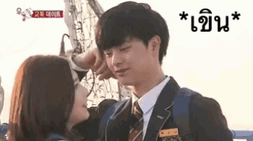 a man in a suit and tie is touching the forehead of a woman .