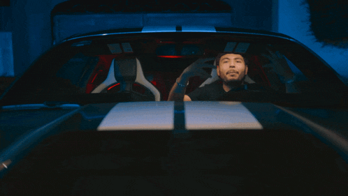 a man sits in the driver 's seat of a car with his eyes closed