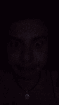 a close up of a person 's face in the dark with a button in the corner
