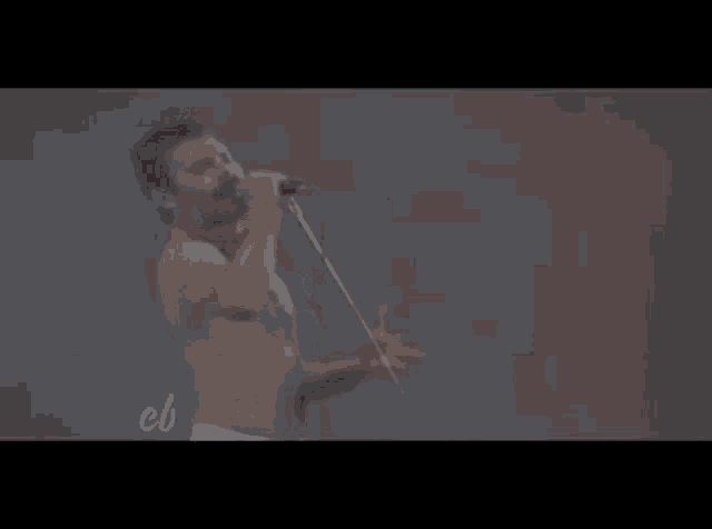 a man without a shirt is singing into a microphone on a stage .