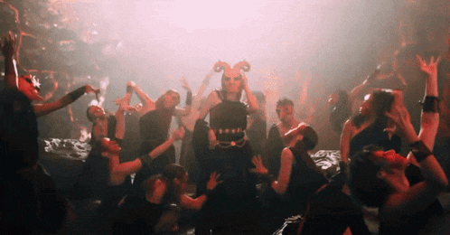 a group of people are dancing in a dark room with a red light behind them