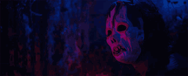 a close up of a person wearing a skeleton mask in a dark room
