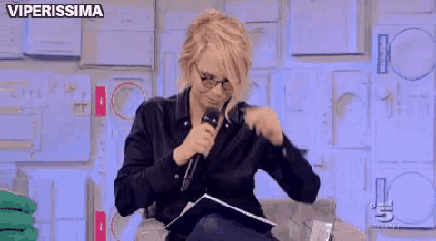 a woman sitting on a couch holding a microphone with the words viperissima on the bottom right