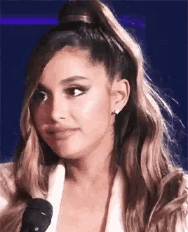a close up of a woman 's face with a ponytail and a microphone .