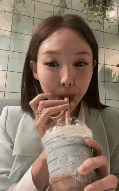 a woman is drinking a starbucks drink through a straw