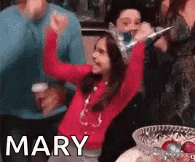 a girl in a red sweater is celebrating with her arms in the air and the word mary is on the bottom of the image .