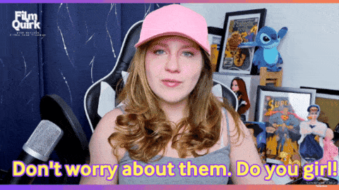 a woman wearing a pink hat says " do n't worry about them do you girl " in front of a microphone