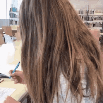 a woman with long hair is holding a blue pen
